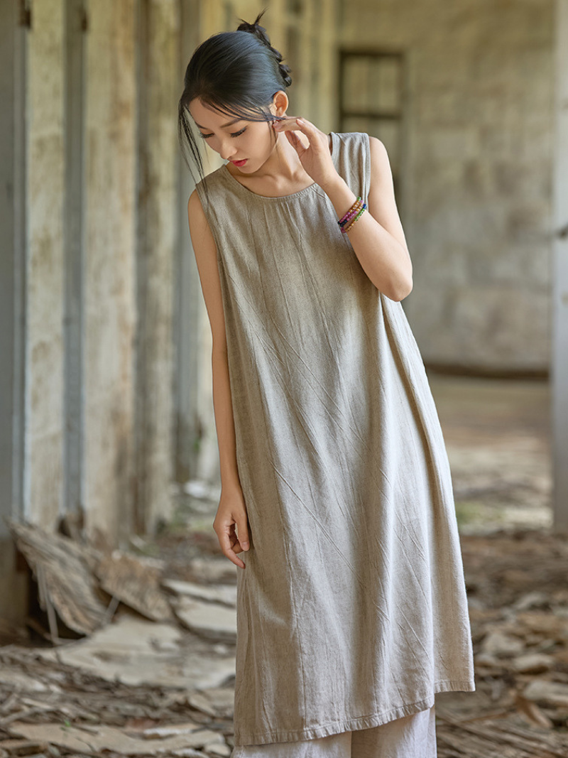 Woman wearing a beige sleeveless dress in a rustic setting