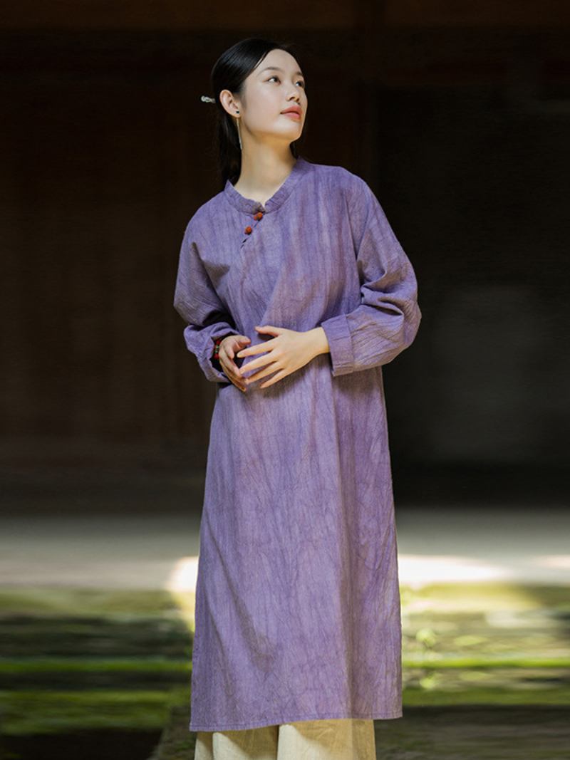 Woman wearing a long purple dress standing against a blurred natural background