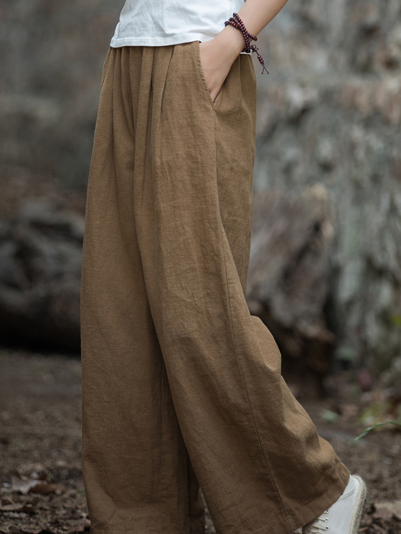 Women's  wearing brown wide-leg pants with a blurred natural background