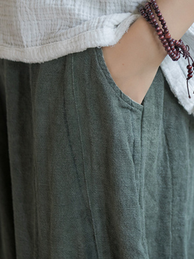 Person wearing a green garment with a white shirt underneath, focusing on the neckline.