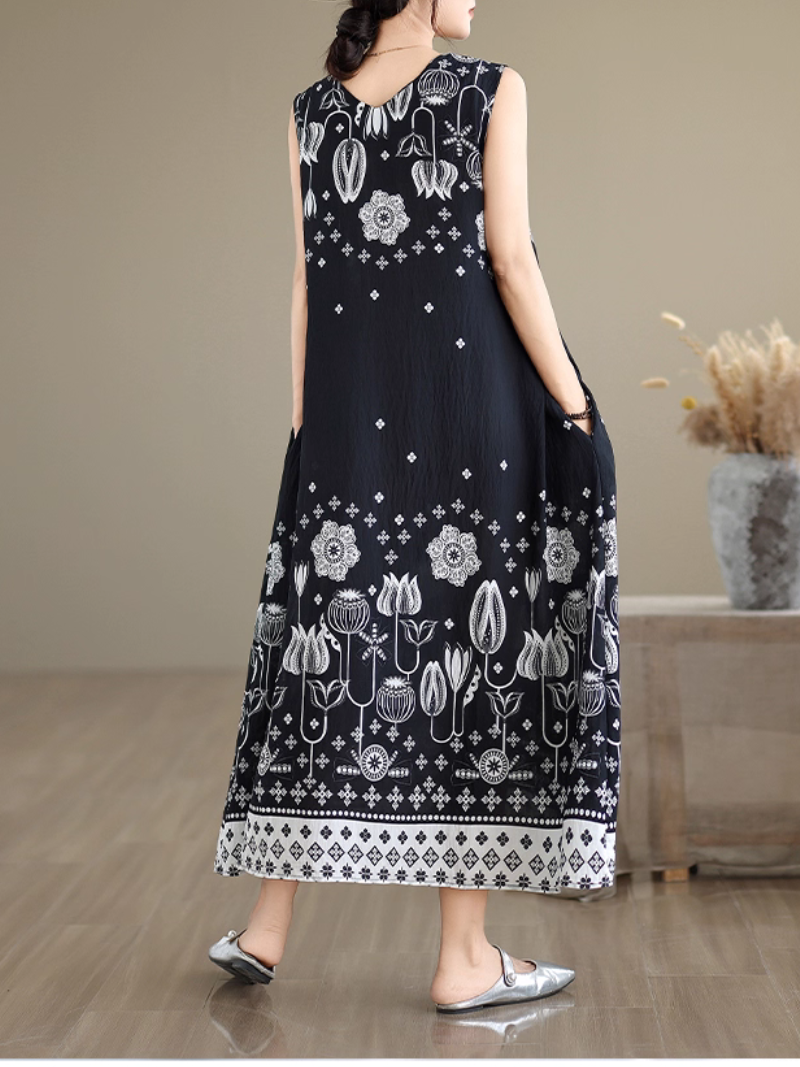 Woman wearing a black sleeveless dress with white floral patterns in a room.