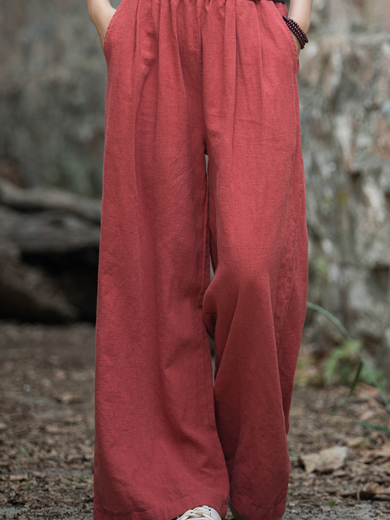 Red pants worn by a person standing in a natural setting with rocks and foliage.