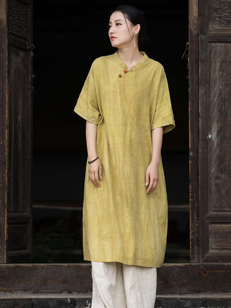 Woman wearing a yellow traditional outfit standing in front of dark wooden doors.