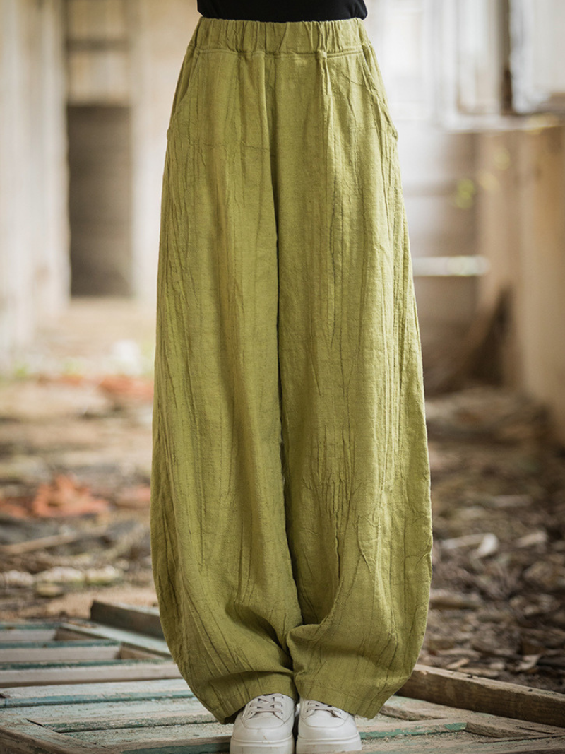 Green wide-leg pants worn by a person in an indoor setting with wooden floor and blurred background