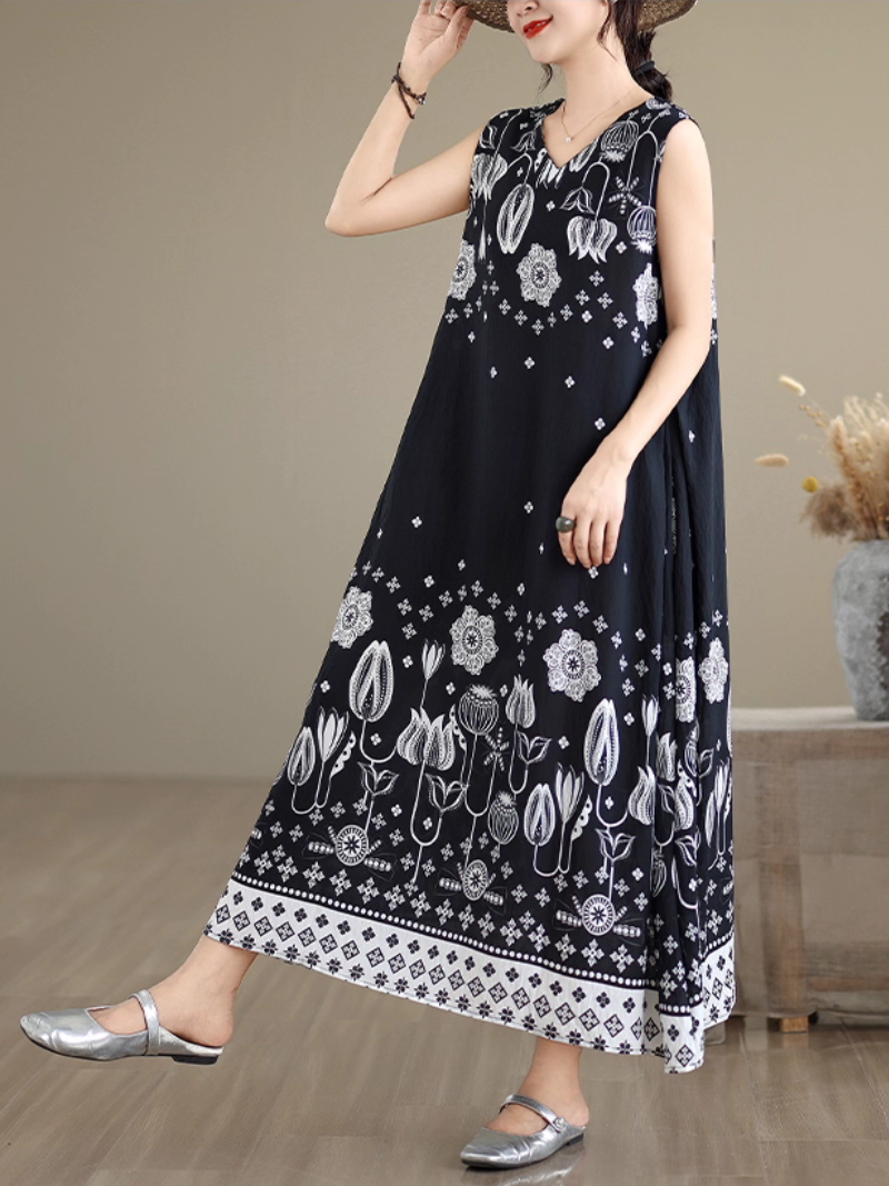 Woman wearing a black sleeveless dress with white floral patterns on a plain background