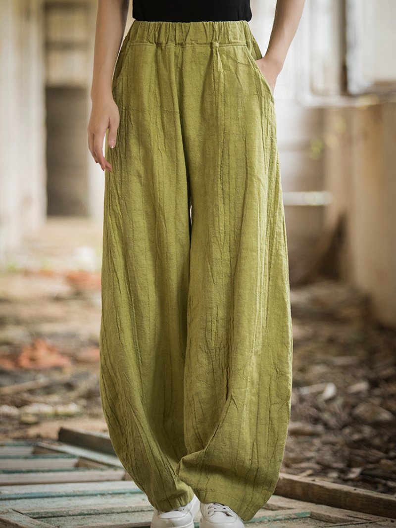 Women's wearing green wide-leg pants in a rustic indoor setting