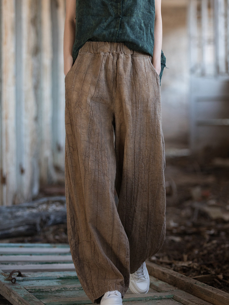 Trendy  wearing brown wide-leg pants and a green top in an outdoor setting.