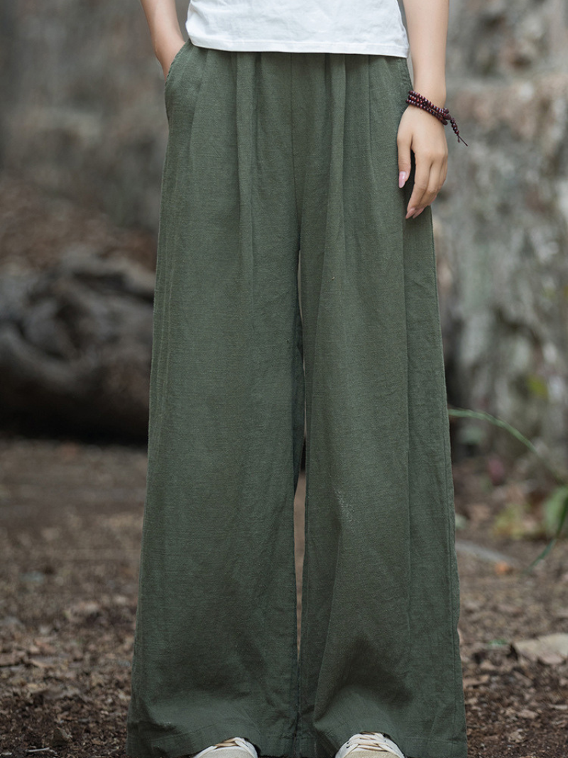 Person wearing green wide-leg pants with a blurred natural background