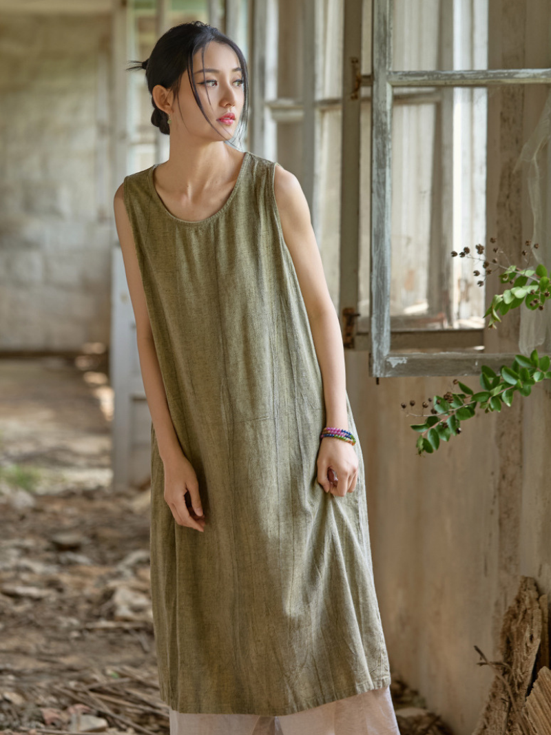 Woman wearing a green sleeveless dress in a rustic indoor setting