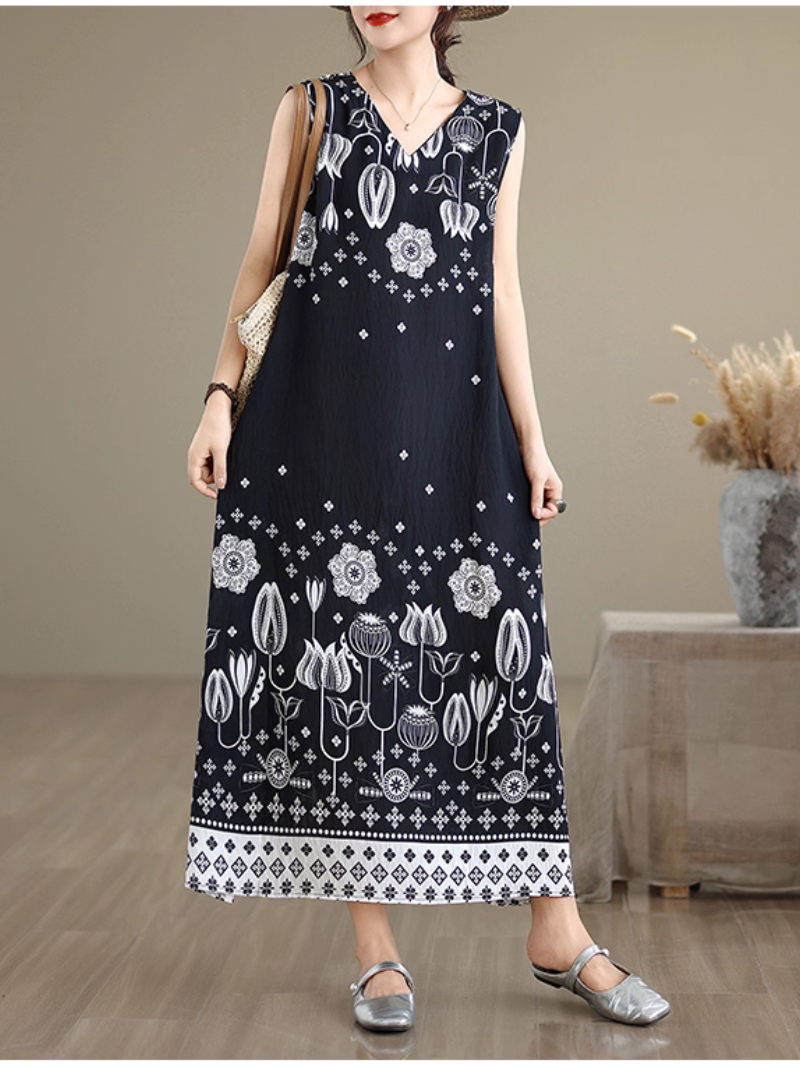 Woman wearing a black sleeveless dress with white floral patterns in an indoor setting.