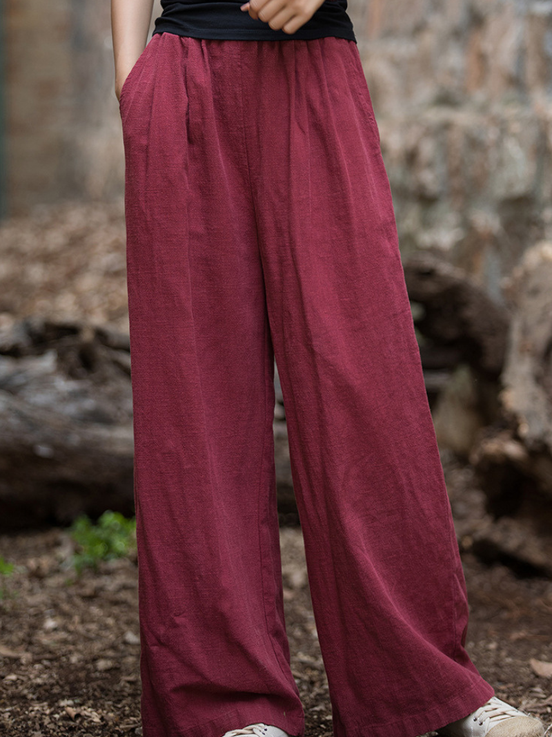 Maroon wide-leg pants worn by a person against a natural background.