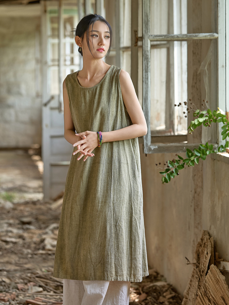 Woman wearing a green dress standing in a rustic indoor setting with wooden walls and a window.