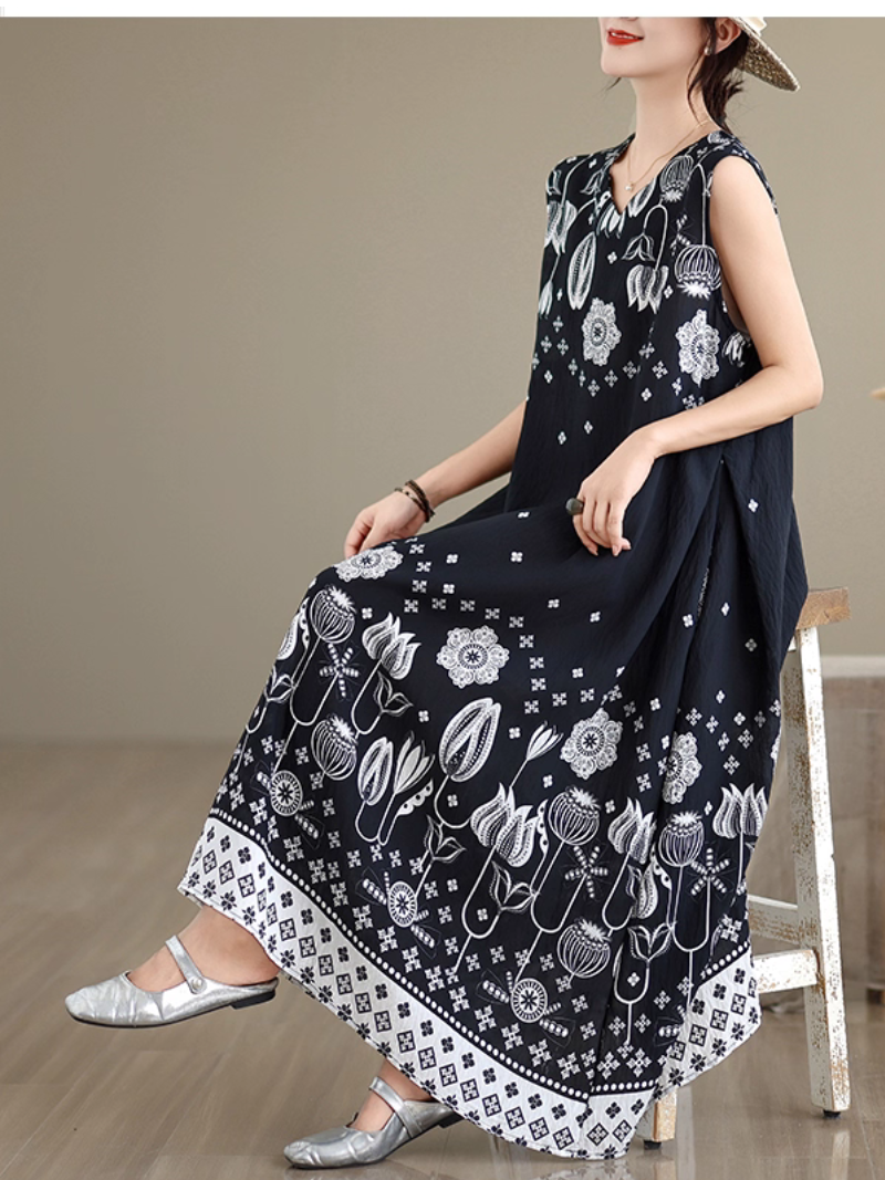 Woman wearing a black dress with white floral patterns, sitting on a chair.