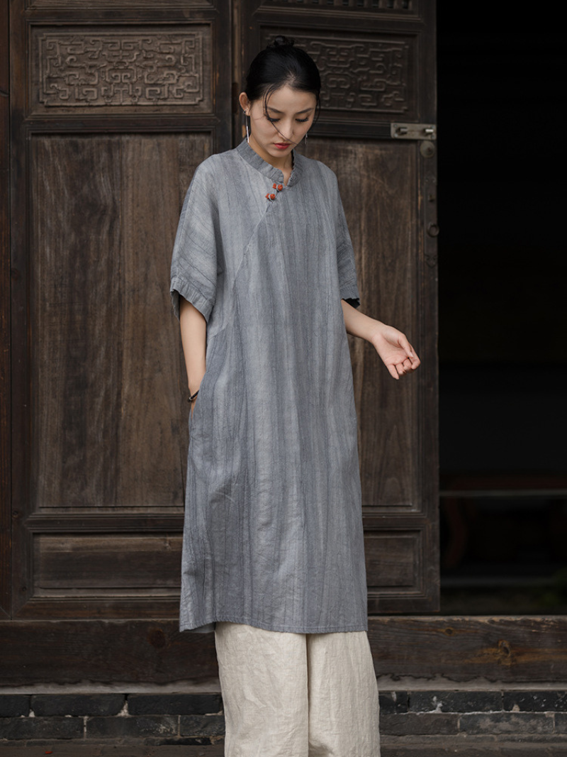 Woman wearing a gray dress standing in front of a wooden door.
