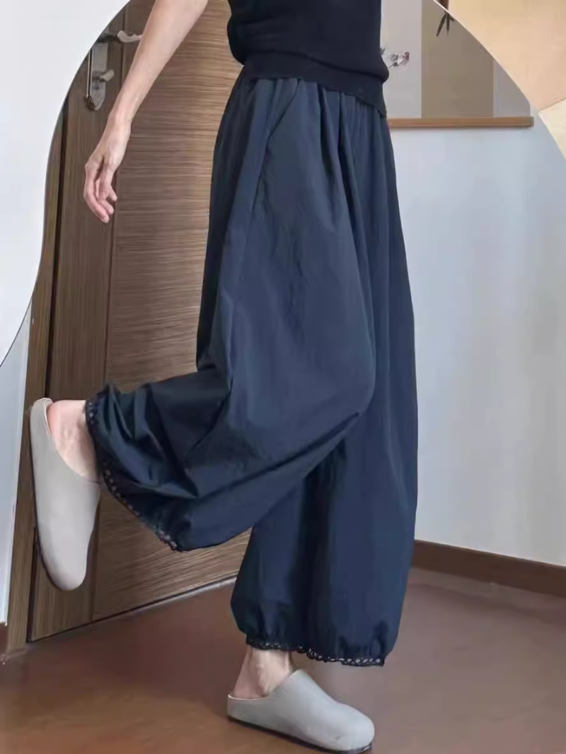 Women's wearing dark blue wide-leg pants and white slippers standing in a room.