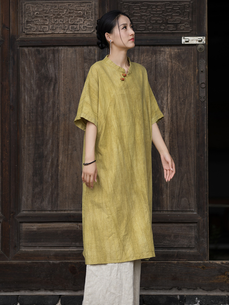 Woman wearing a yellow dress standing in front of a wooden door.