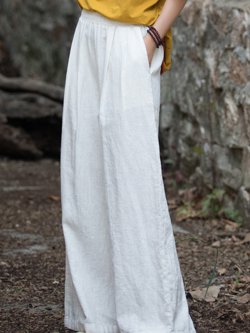 Person wearing a long white skirt with a blurred natural background